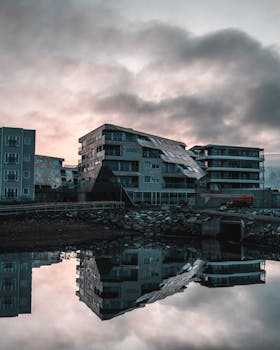 平静的水面映照出当代海滨建筑在戏剧性日落中的景象