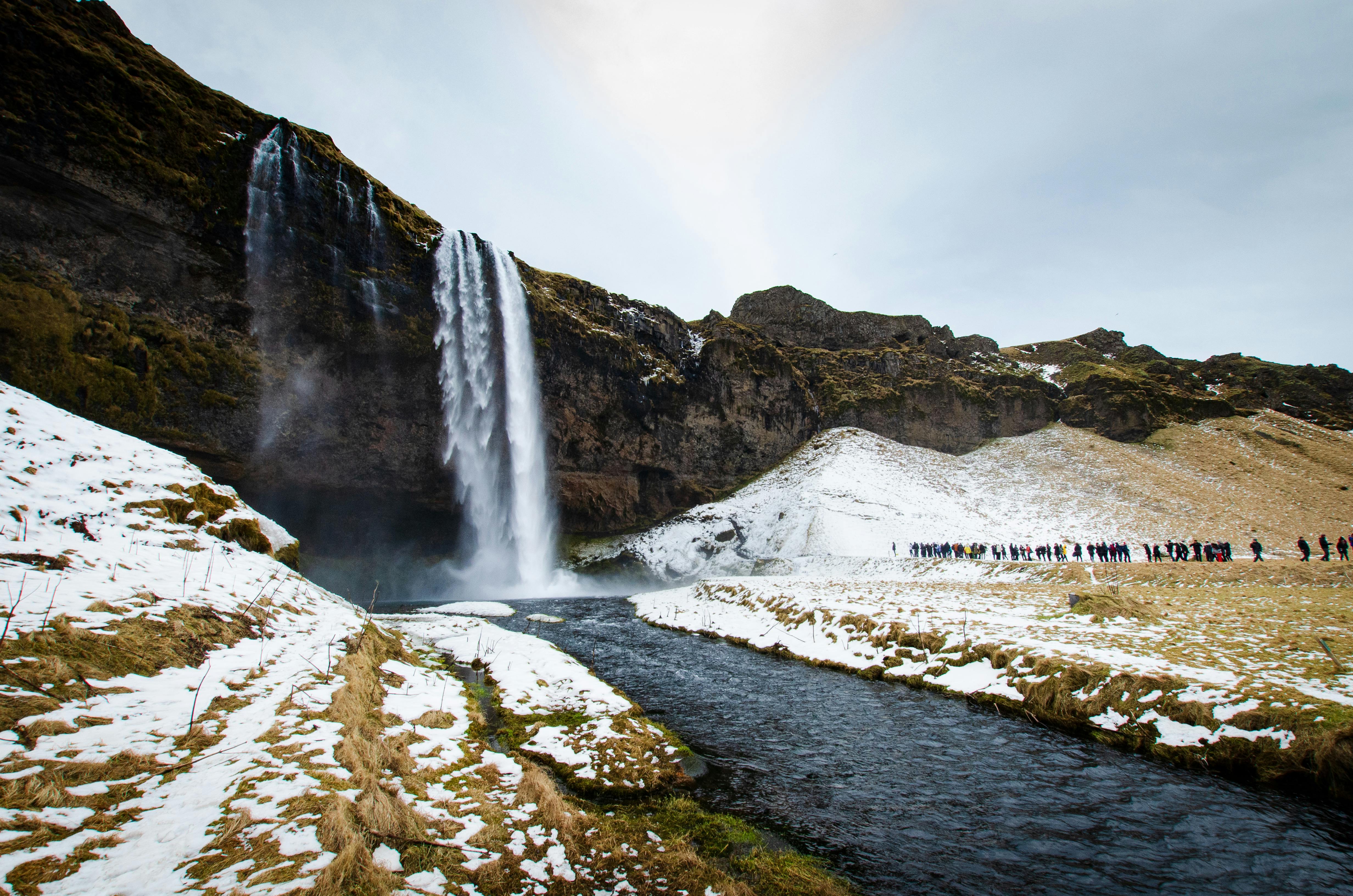 Captivating view of Seljalandsfoss waterfall in Iceland with snowy landscape and river.