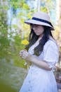 Woman Wearing Hat and Eyeglasses Holding Yellow Flower