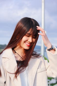 一位美丽的女子在户外快乐地微笑，秀发随风飘扬，尽显自然之美