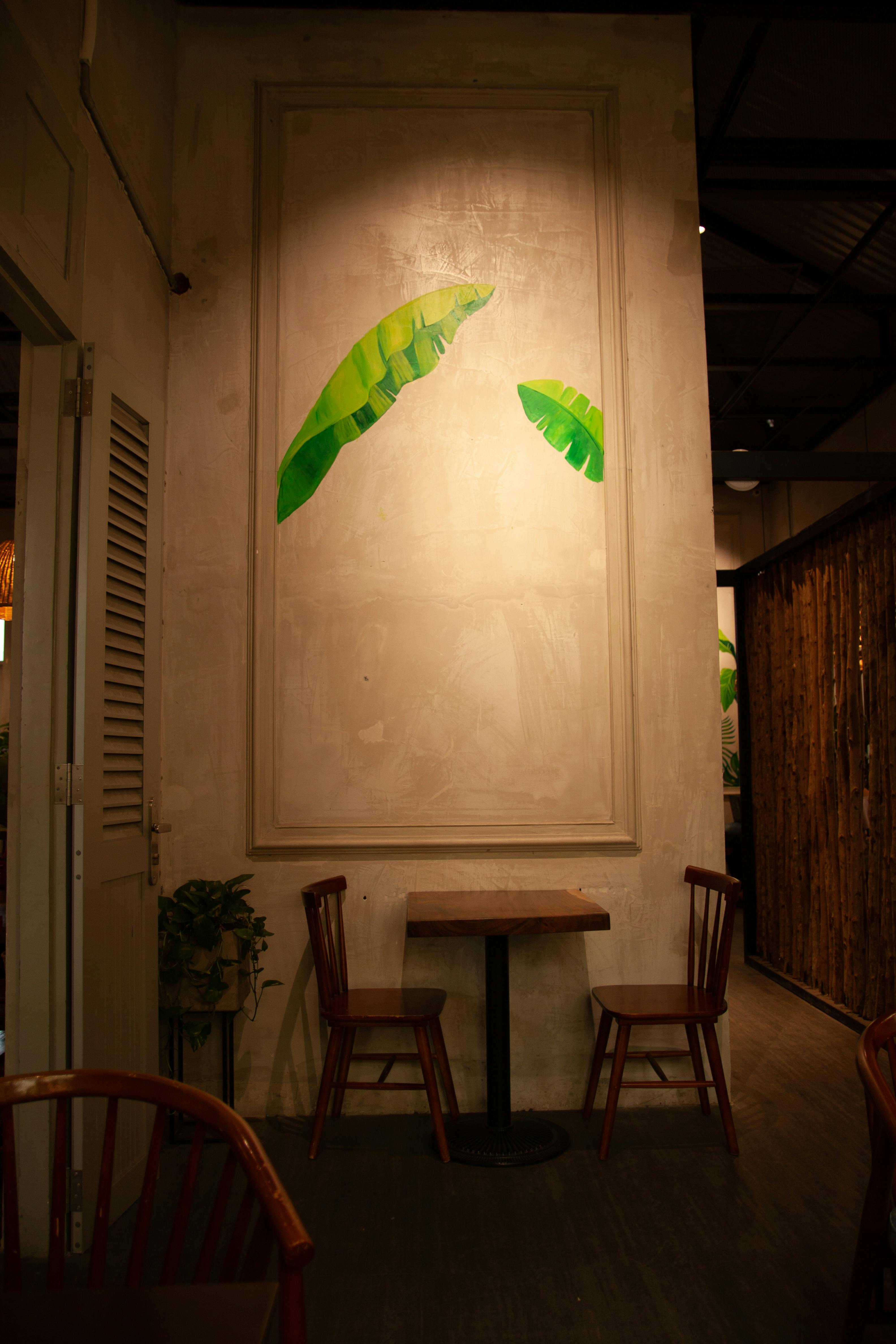 温暖的室内餐厅设有座椅，并装饰着充满活力的叶墙艺术
