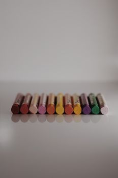 充满活力的蜡笔系列整齐排列，在反射表面上呈现出广泛的色彩光谱