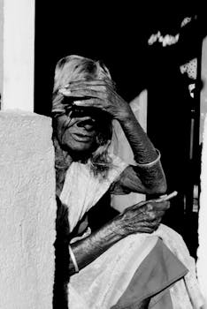 一位穿着传统服装的斯里兰卡人，遮挡着眼睛免受阳光照射的黑白肖像