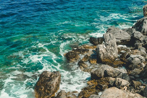 A rocky shoreline with blue water and rocks