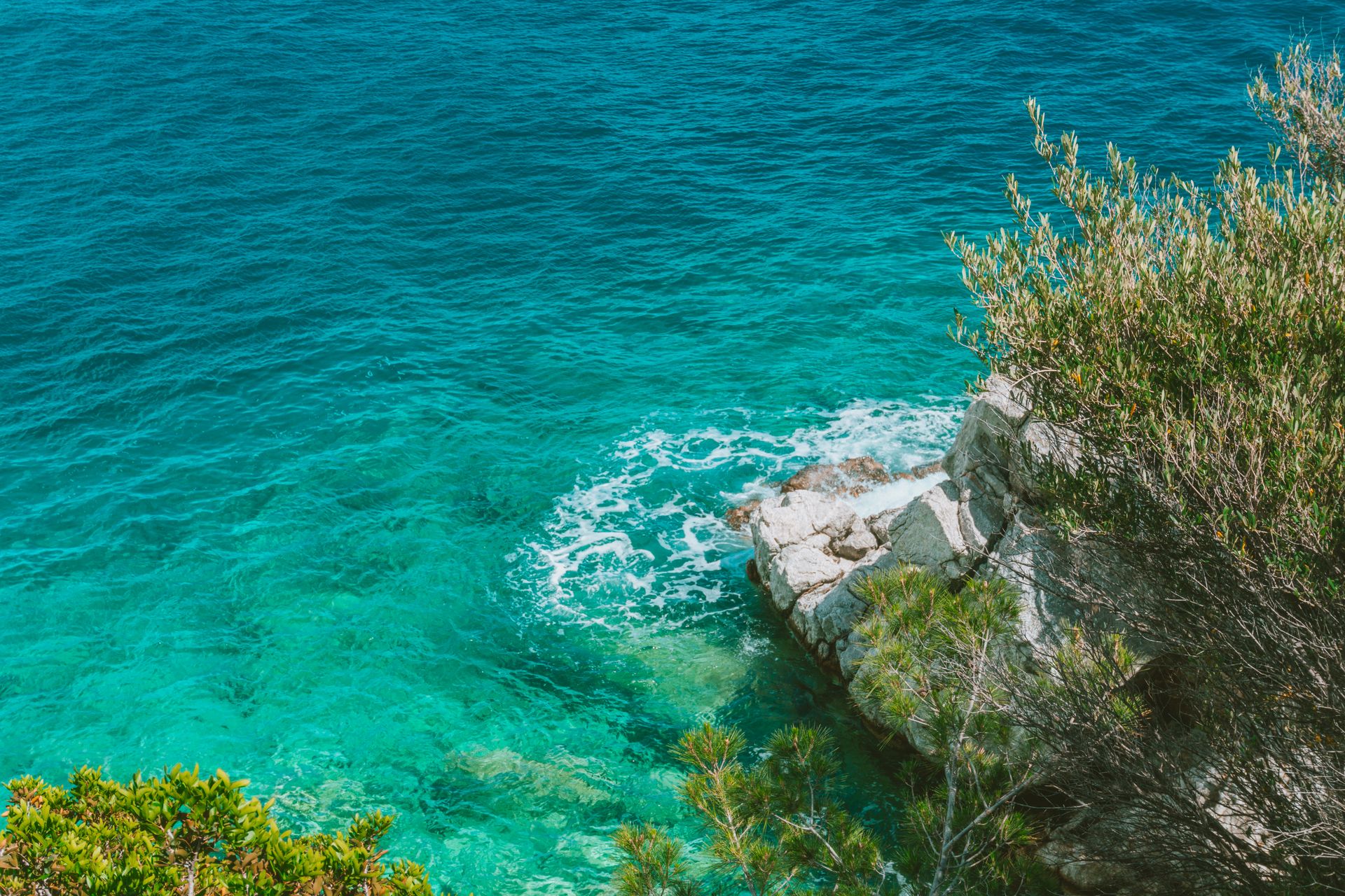 Stunning view of emerald waters and rocky seashore in summer sunlight.