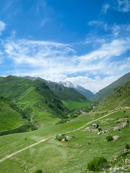 Free Discover the serene beauty of a lush green valley surrounded by majestic mountains under a bright blue sky. Stock Photo