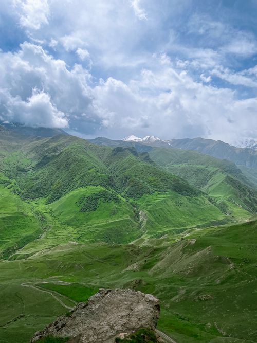 Free A breathtaking view of lush green mountains under a dynamic cloudy sky, ideal for travel enthusiasts. Stock Photo