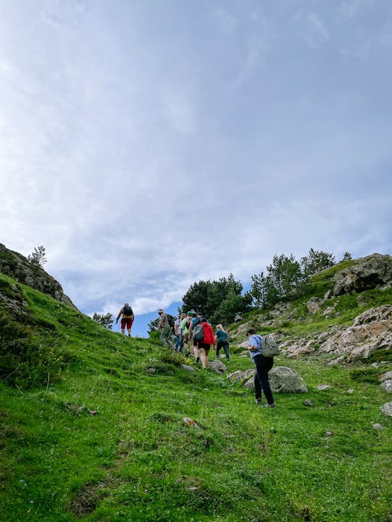 People hiking up a steep hill with a cloudy sky