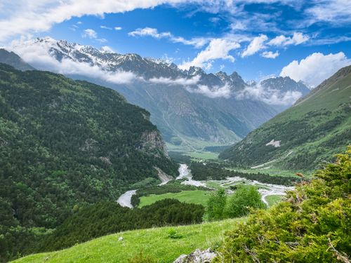 Free Breathtaking mountain landscape featuring a river meandering through a lush green valley. Stock Photo