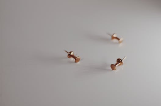 Artistic close-up of metallic gold thumb tacks on a smooth white background.