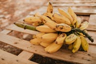 质朴的木托盘上躺着一堆成熟的黄色香蕉，非常适合作为健康零食的形象