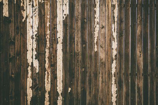 Close-up of a rustic wooden fence with peeling paint, showcasing the beauty of weathered textures.