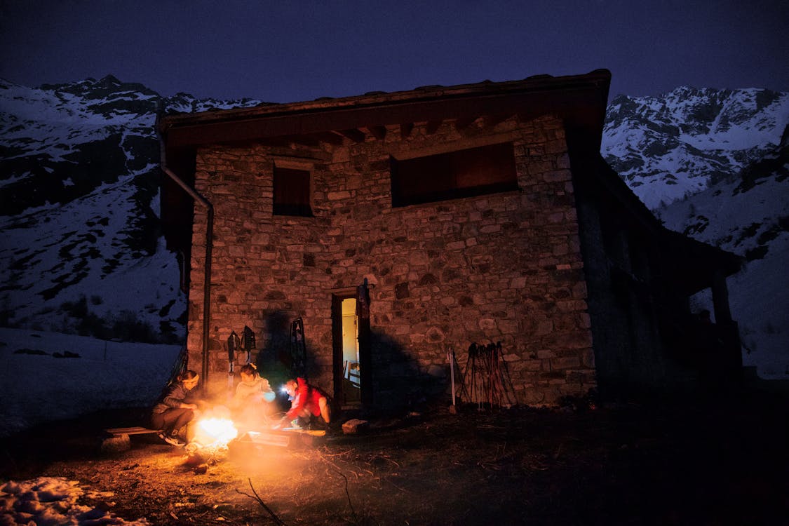 A person sitting by a fire in front of a house