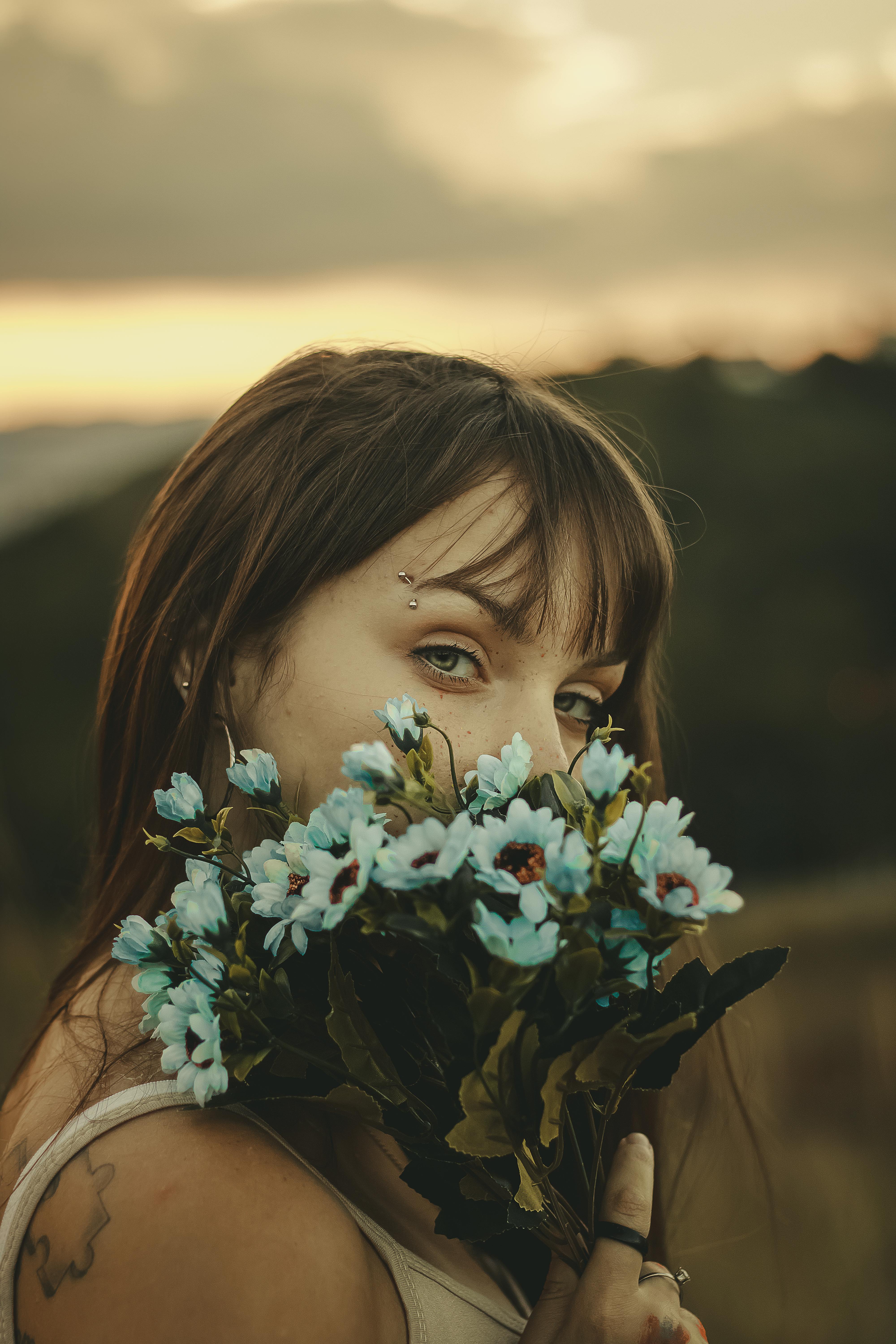在巴西贝洛奥里藏特，一名手持花束的年轻女子站在日落背景前
