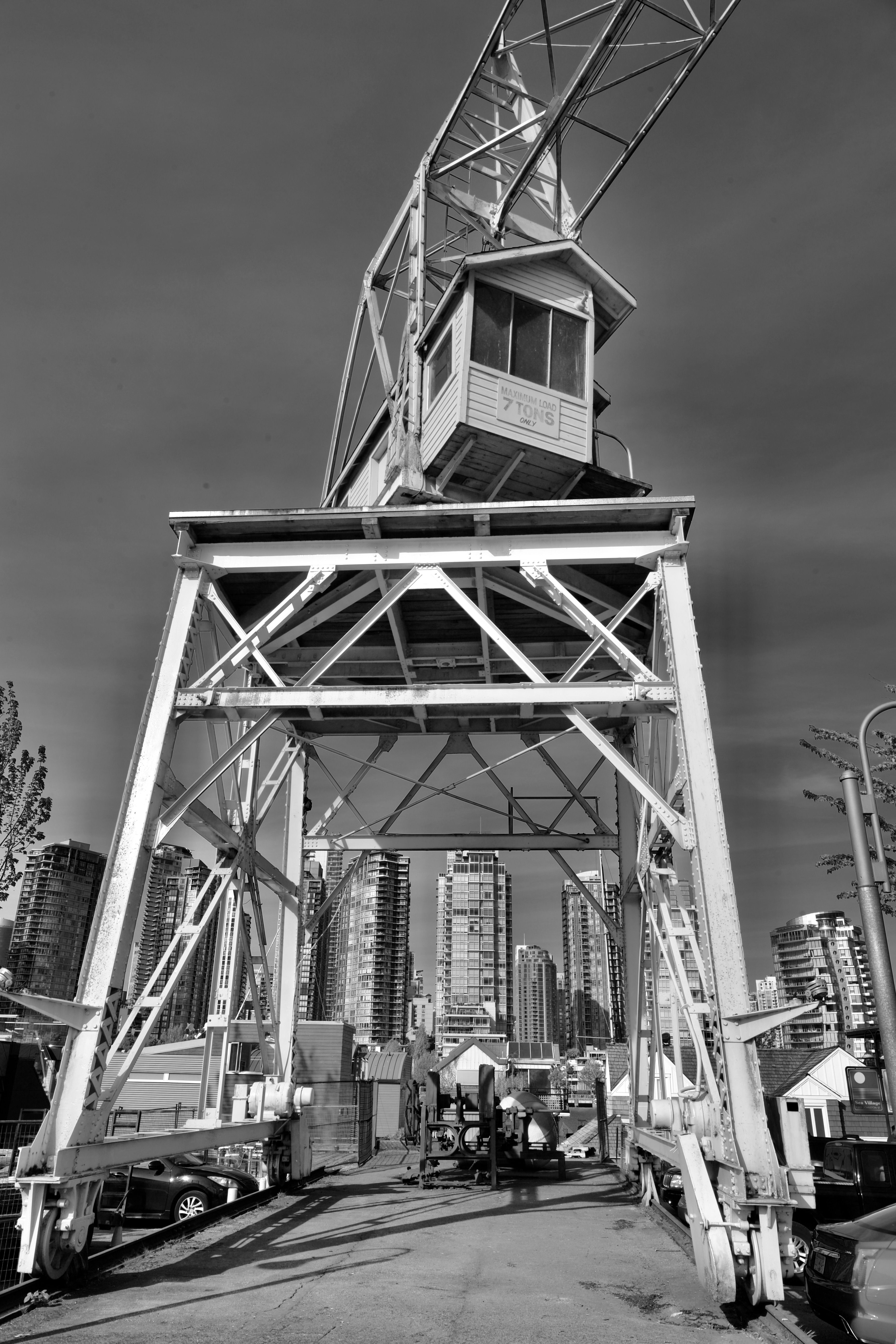 A striking black and white image of an industrial crane with Vancouver's skyline in the background.