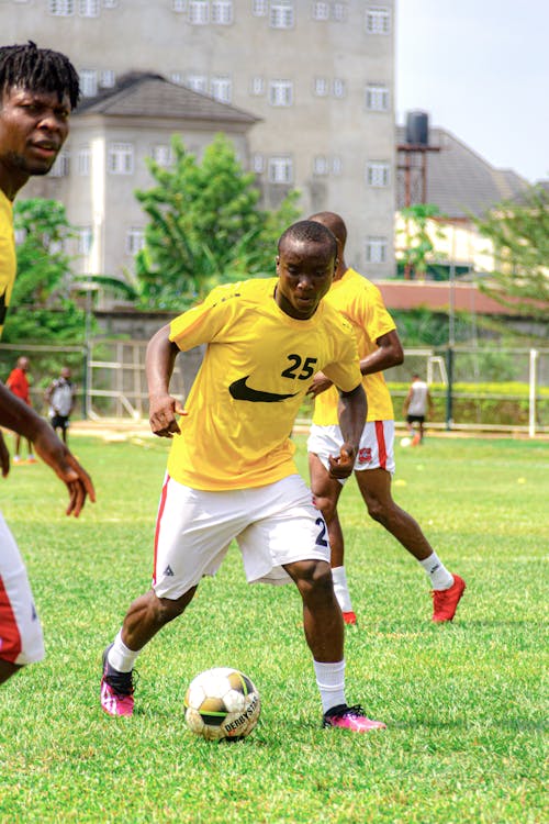 Two men in yellow shirts playing soccer on a field