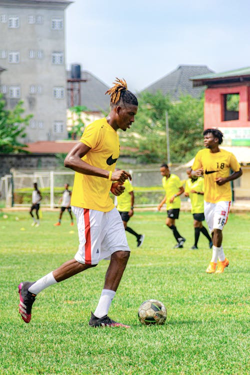 A man in yellow shirt kicking a soccer ball