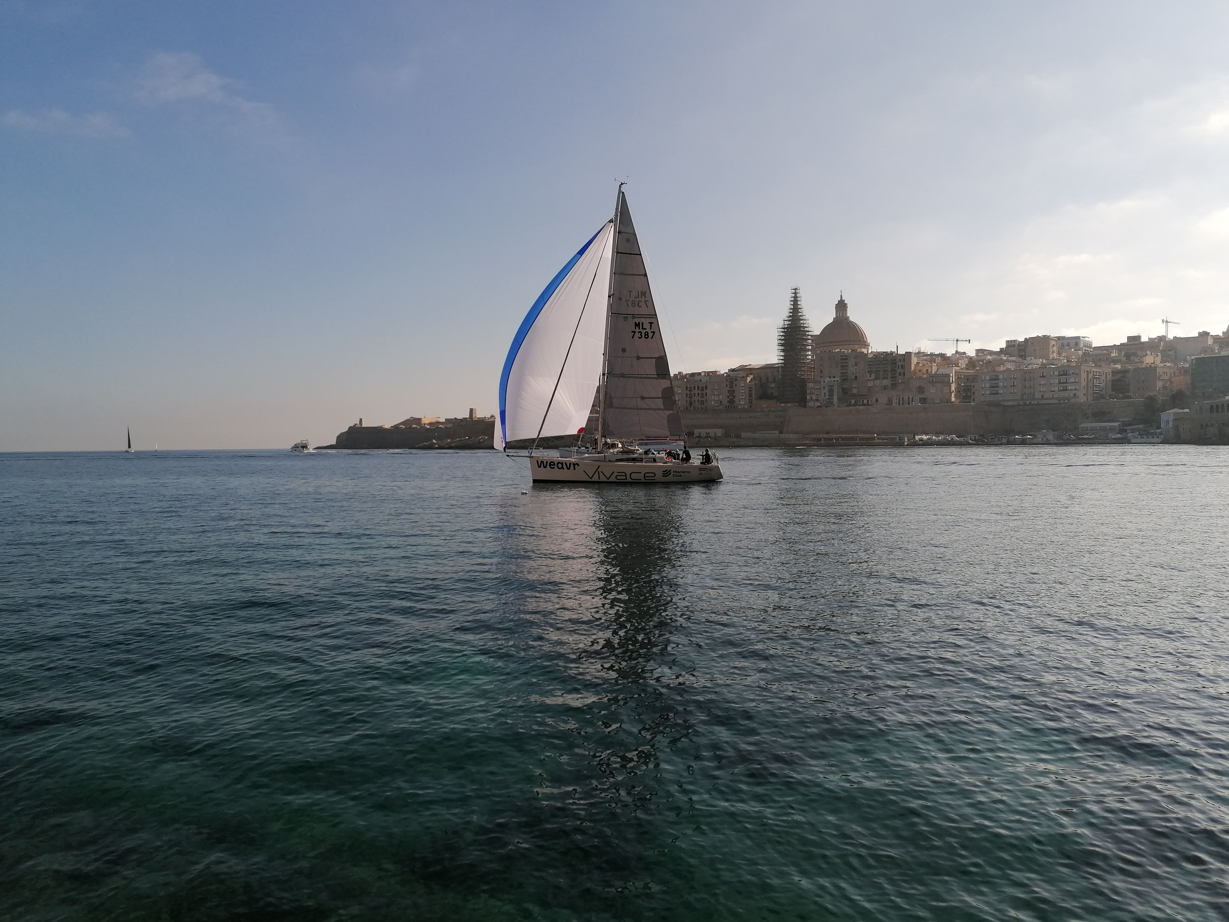 Ultimate Best Sailing Adventure with Malta Sailing Experiences Review 2026 - A sailboat gliding on the calm sea near Valletta, Malta, with cityscape in the background.