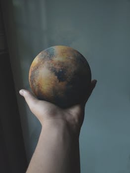 在光线昏暗的房间里，一只手握着色彩缤纷的星球般的球体