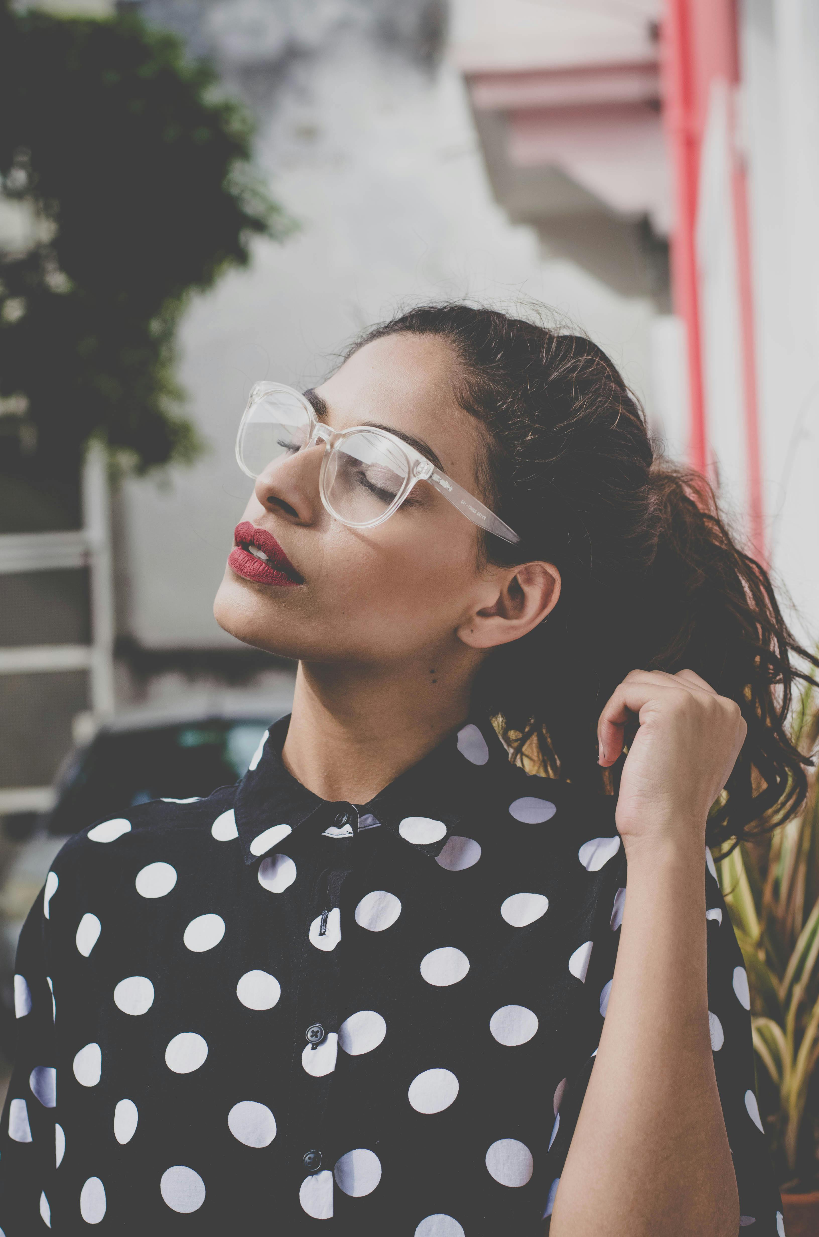 一位穿着圆点衬衫、戴着眼镜的女人在户外享受着阳光明媚的一天