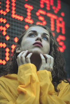 Portrait of a woman in a yellow jacket with a thoughtful expression, gazing upward.
