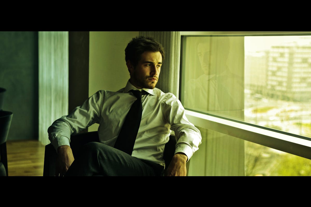 Musician walking off stage holding a guitar with stage lights behind
