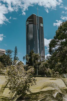 在澳大利亚布里斯班，一座现代摩天大楼矗立在郁郁葱葱的绿化中，映衬着蔚蓝的天空