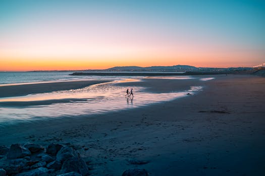 A couple enjoys a romantic walk along the beach during a beautiful sunset.