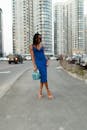 一位时尚女士穿着蓝色连衣裙，自信地站在城市街道上