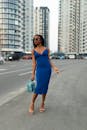 一位穿着蓝色连衣裙的时髦女人，走在高楼林立的城市中