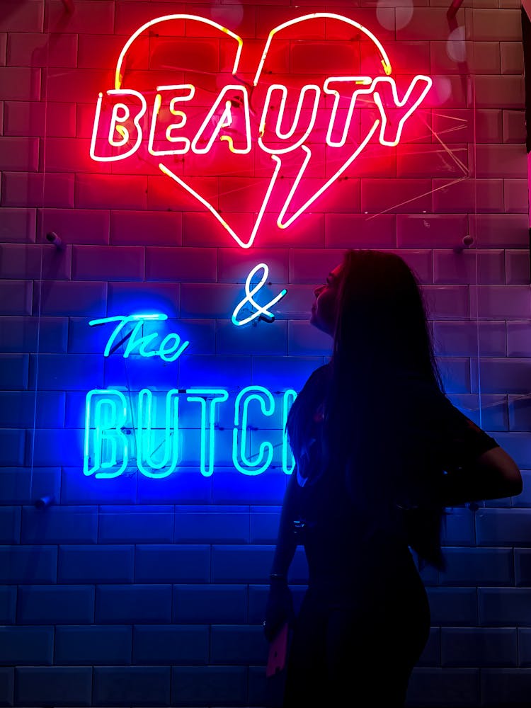 Woman Standing Near Red And Blue Neon Light Signage