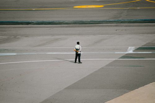 Free Ground staff member in uniform standing on airport runway ready for aircraft operations. Stock Photo