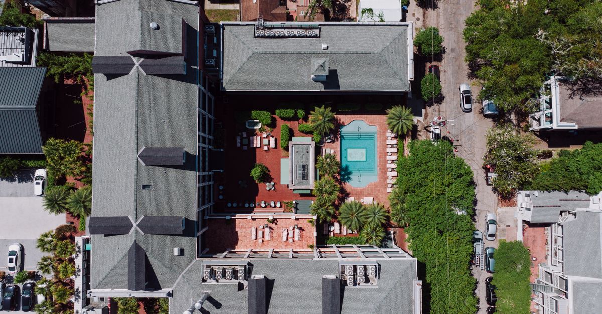Aerial image of a New Orleans building complex featuring a pool and green rooftops.