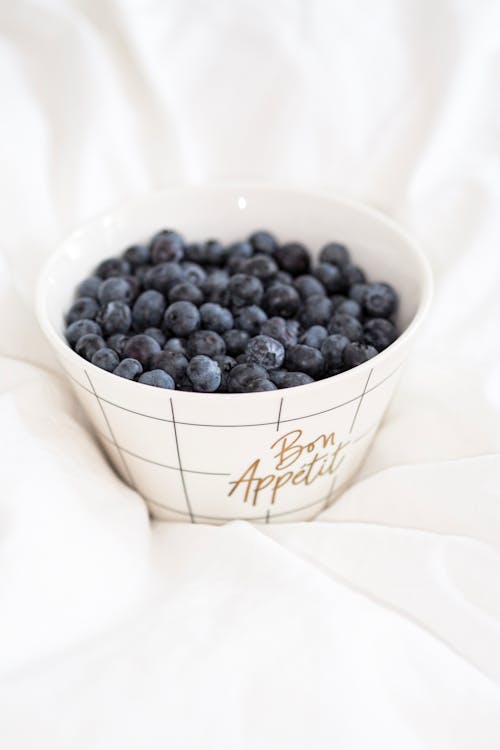 A bowl of blueberries on a bed