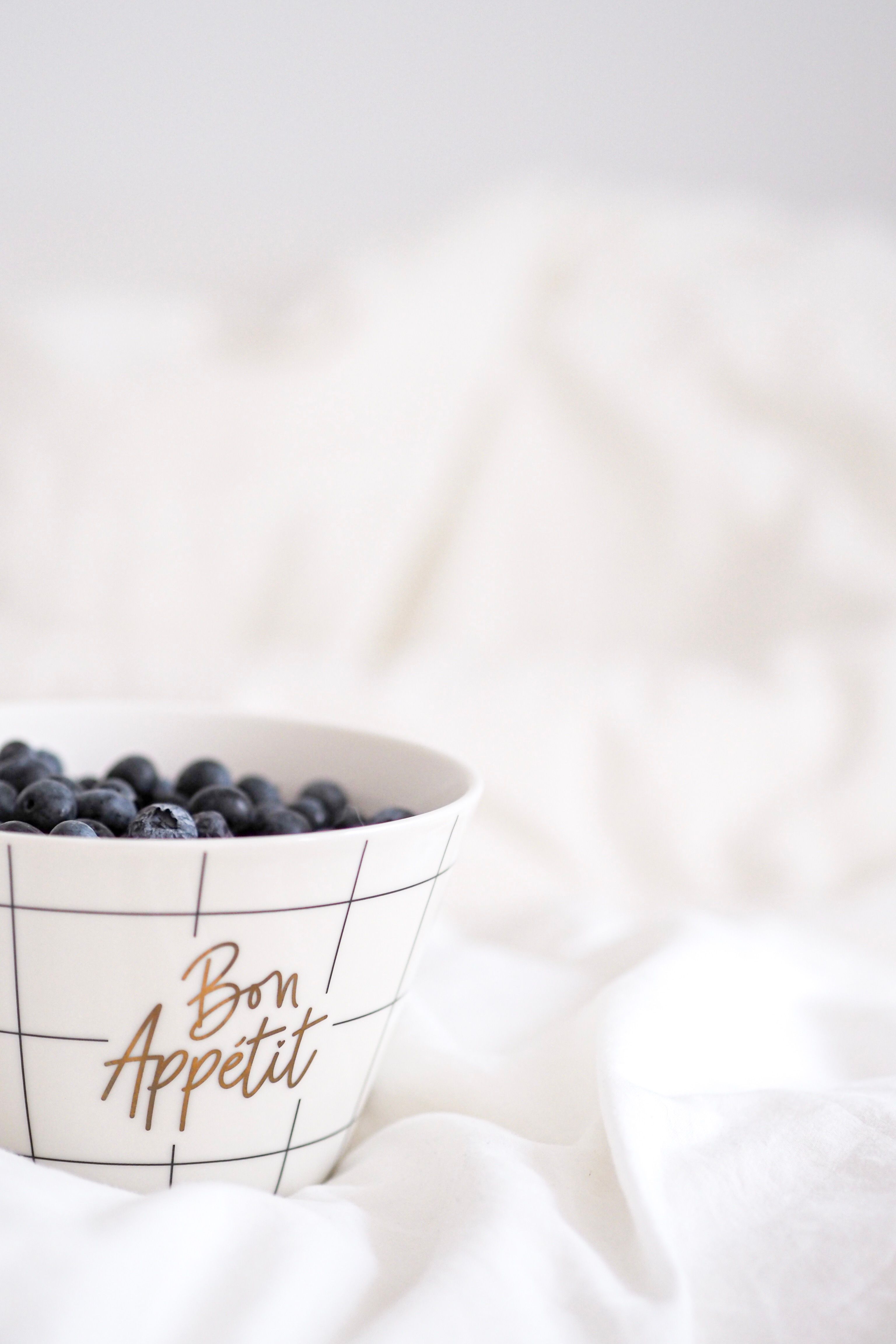 Fresh blueberries in a stylish 'Bon Appétit' bowl on a white background. Perfect for elegant food photography.