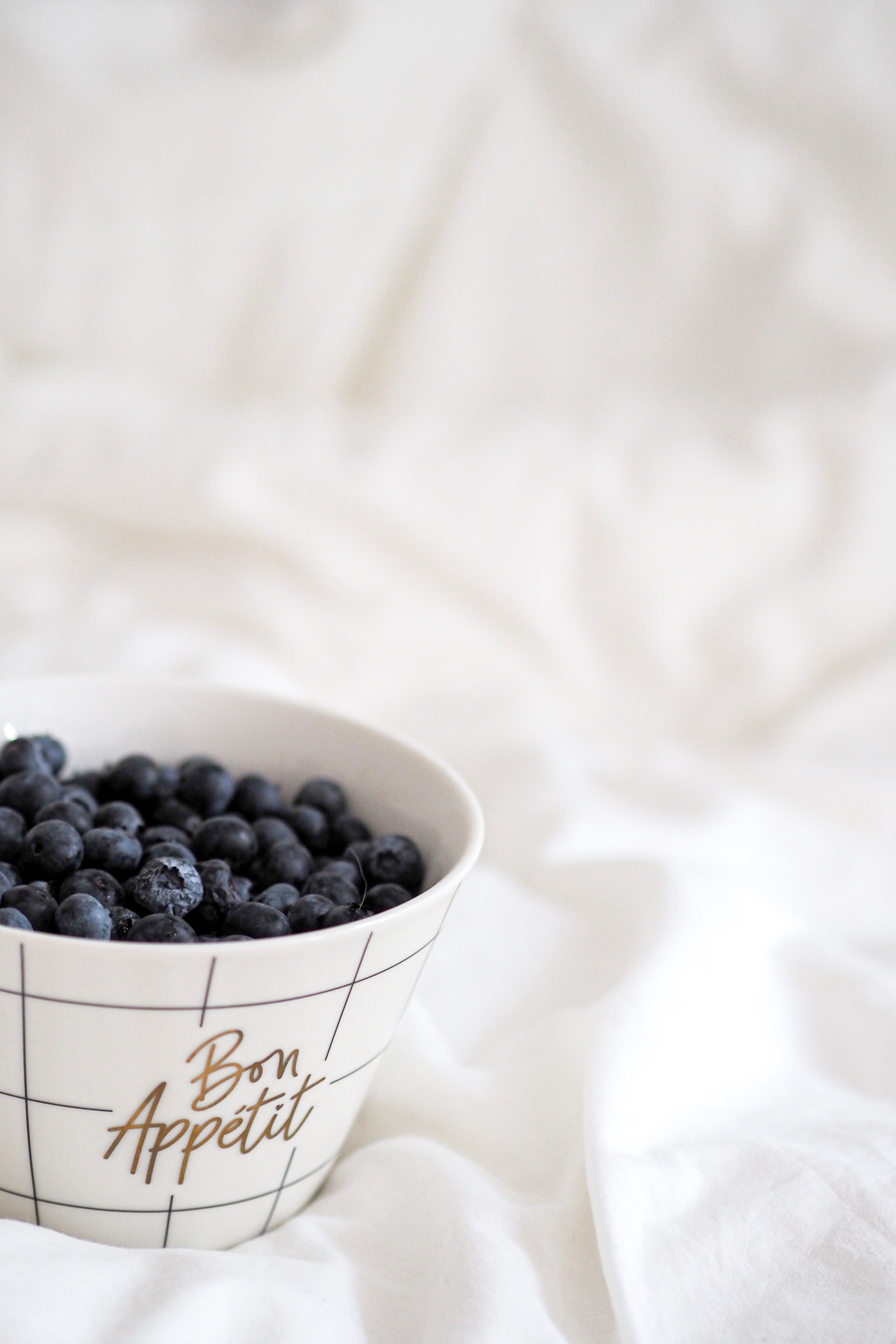 Minimalist arrangement of fresh blueberries in a patterned bowl with 'Bon Appetit', Paris-inspired elegance.