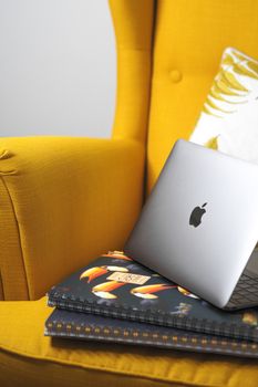 A stylish workspace with a yellow armchair and laptop on notebooks, Paris inspiration.