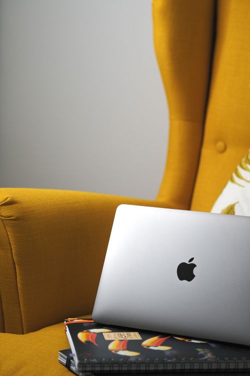 Free A sleek laptop rests on a stylish armchair in a Parisian setting, blending technology with comfort. Stock Photo