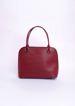 Stylish red leather handbag with handles on a clean white background, perfect for fashion enthusiasts.