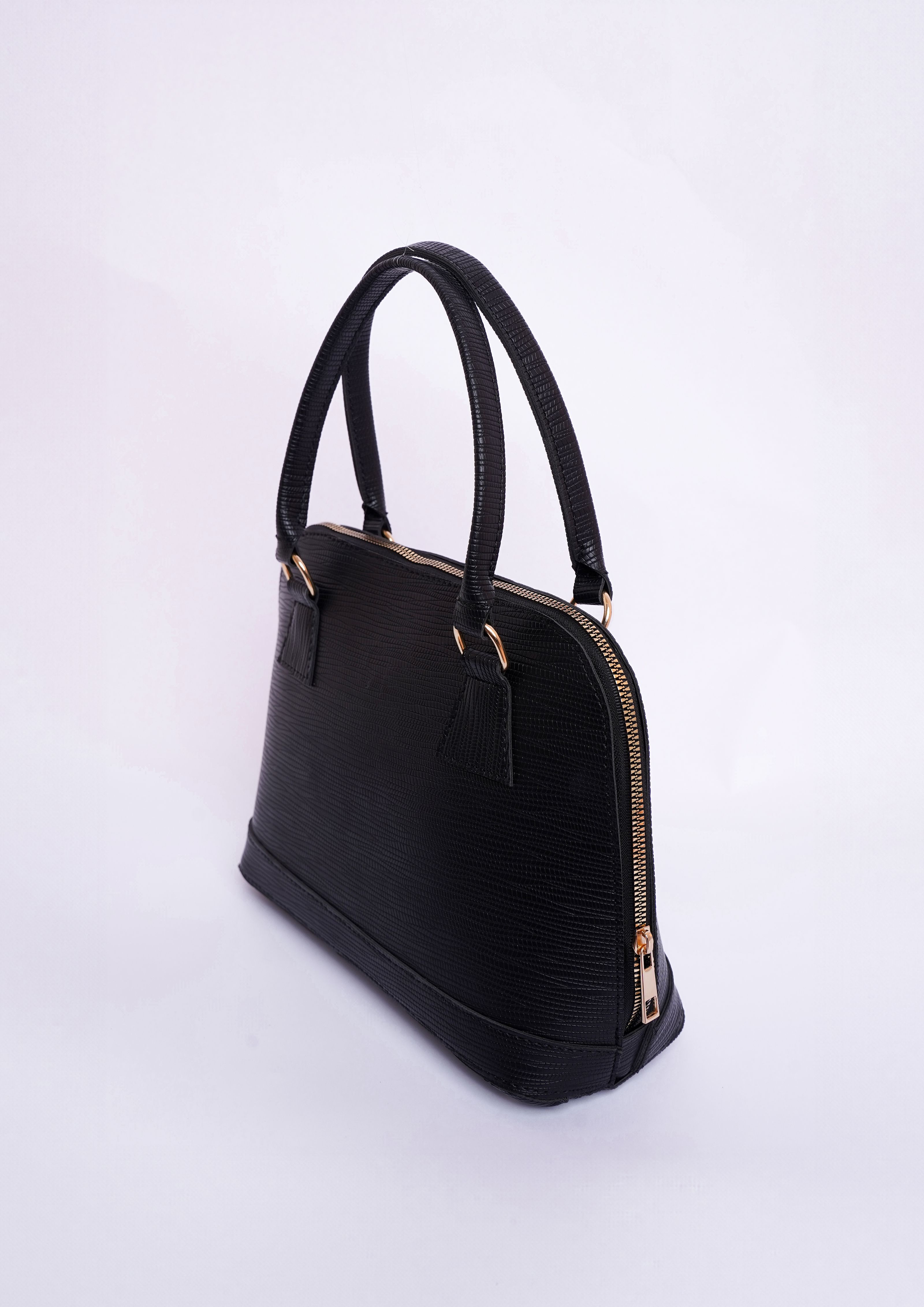Bolsa de moda sofisticada preta com detalhes em dourado sobre um fundo branco brilhante.