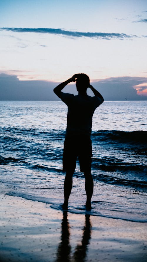 A man standing on the beach at sunset