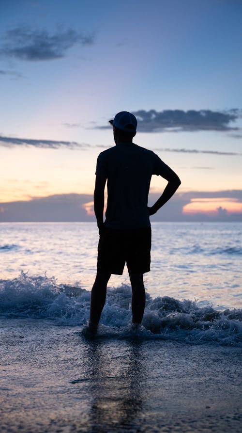 A silhouette of a man standing in the ocean at sunset