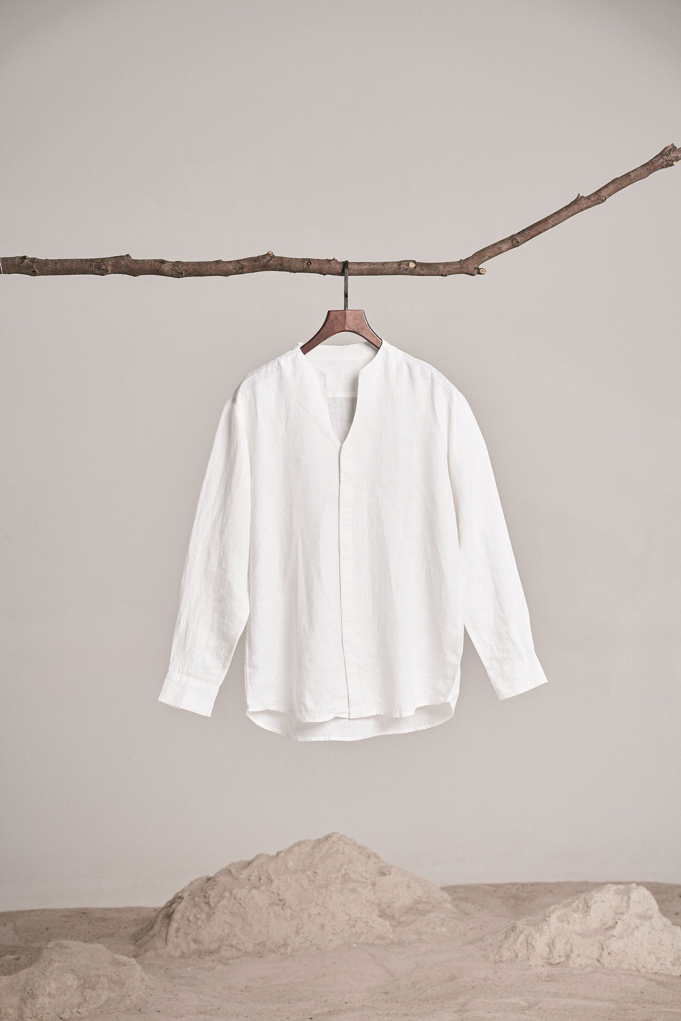 White shirt displayed on a branch, showcasing minimalist fashion aesthetics and natural style.