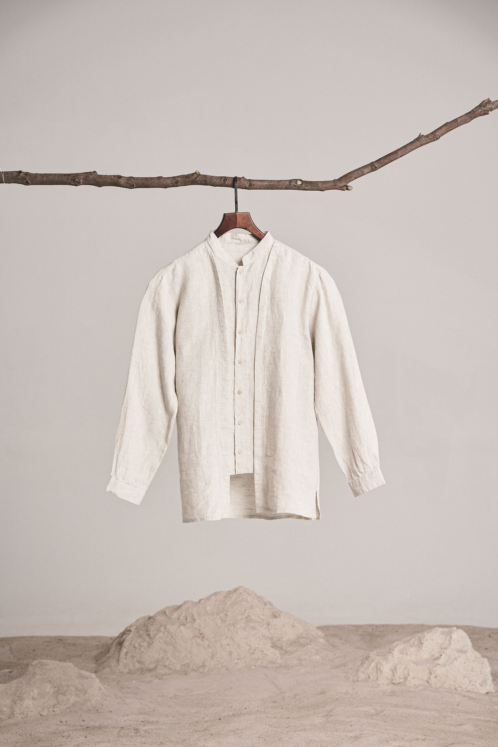 Beige shirt hanging from a branch in a minimalist setting with no people