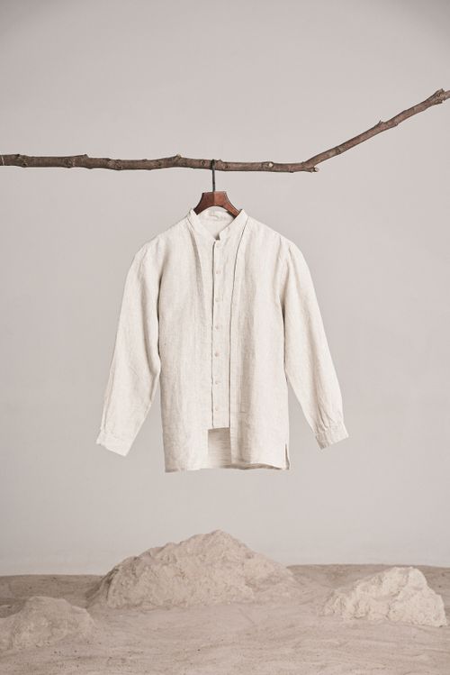 A beige shirt hanging against a plain studio background. Photo by dayong tien on Pexels.