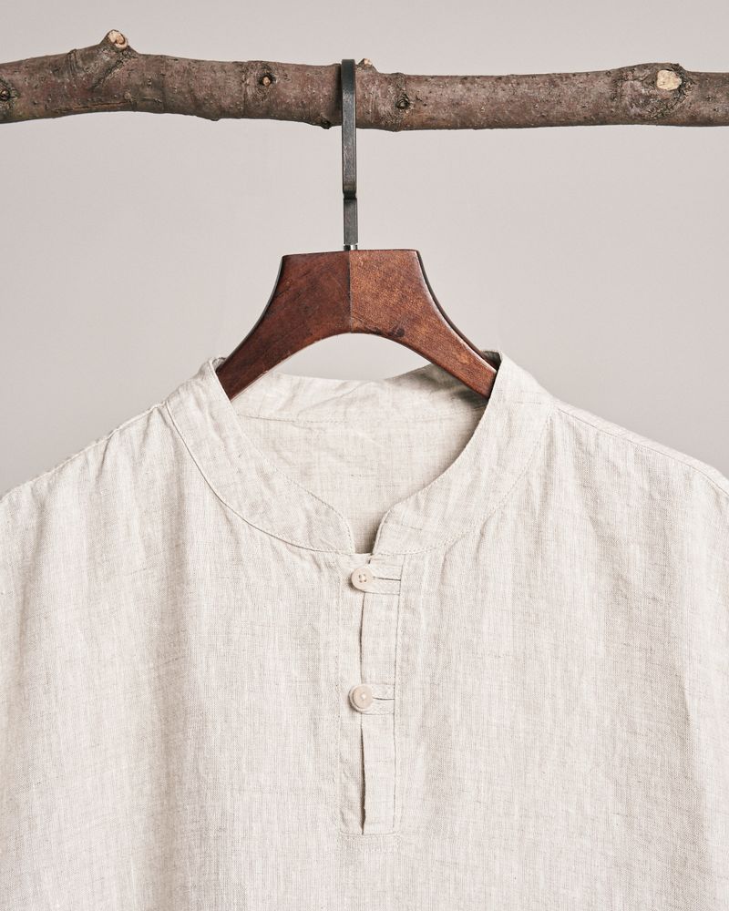 Blus linen polos digantung di hanger kayu dengan latar netral