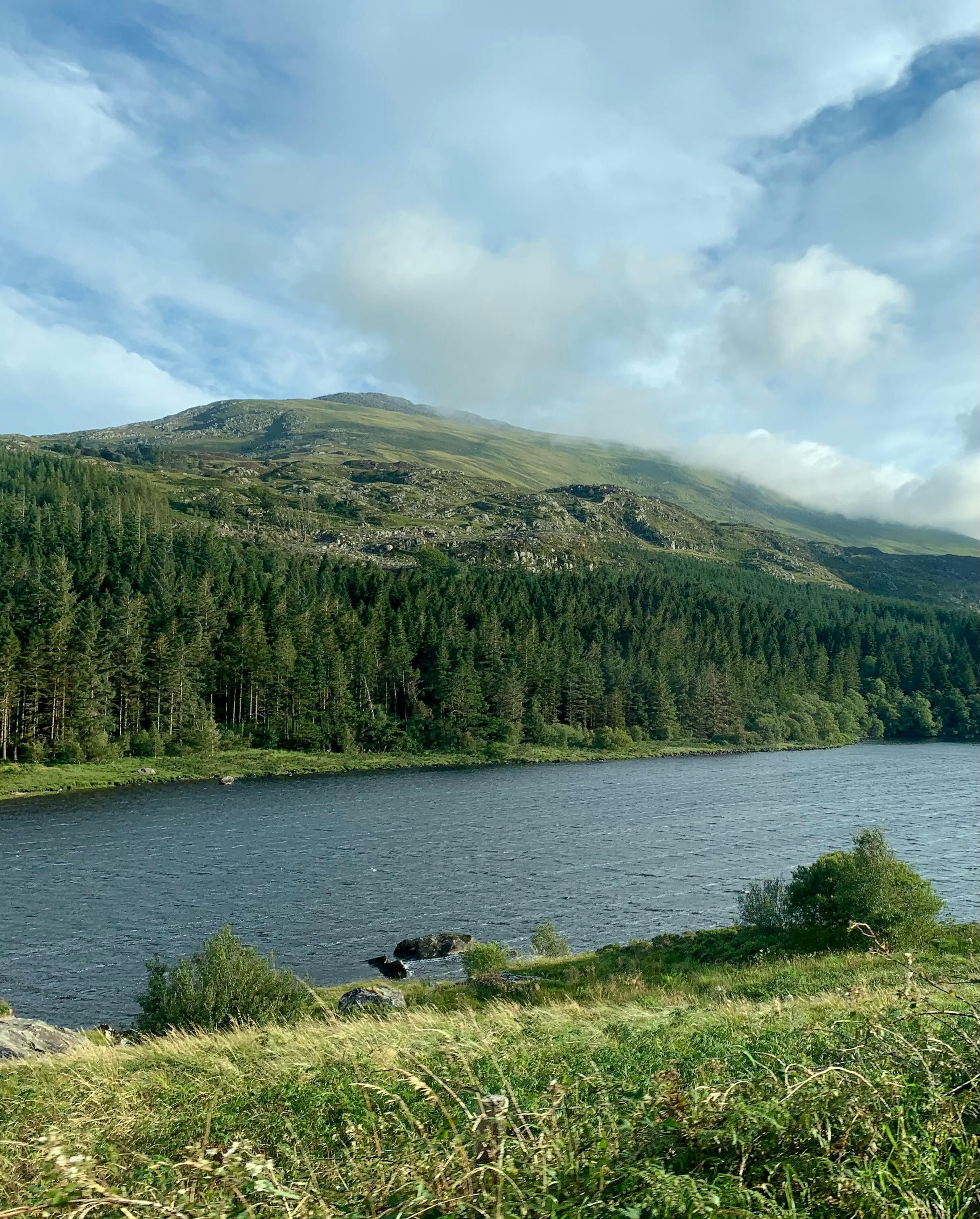 Beautiful landscape of river and forest in Conwy, Wales with hills and clouds.