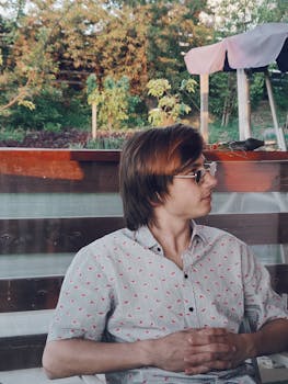 一个穿着时髦、身着图案衬衫的人，在户外享受阳光明媚的日子，侧面肖像显得随意自然