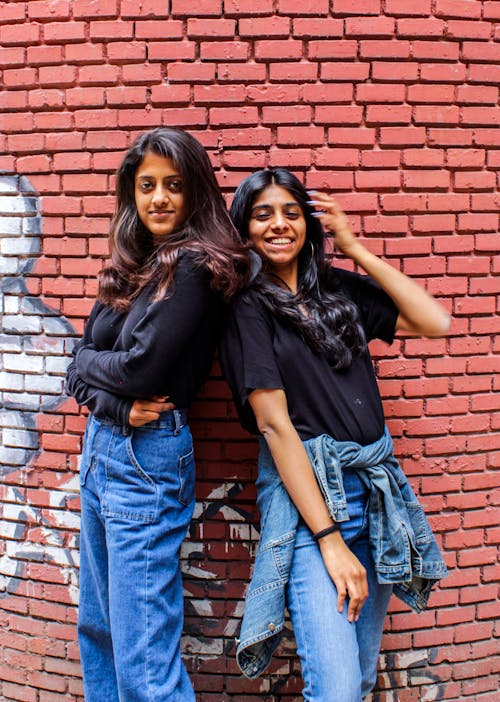 Two Woman In Black Shirts And Blue Denim Jeans