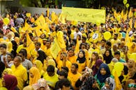 身穿黄色衣服的人群举着旗帜、横幅和气球参加集会，强调团结